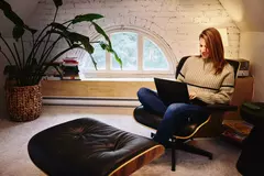 Female sitting in an armchair in a loft working on a laptop