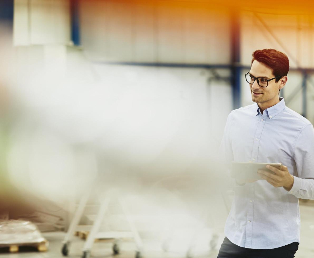 Male worker in a tech environment. Holding papers. Wearing glasses. Factory/logistics. Solid white shirt. Primary color cream. Secondary color yellow/orange.